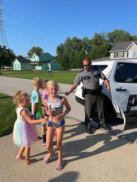 A Mt. Orab police officer hands out popsicles to local children during Operation Freeze Out. Photo provided